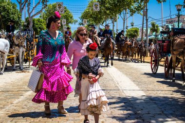 Seville, İspanya - 5 Mayıs 2022 Sevilla 'lılar geleneksel Endülüs tarzında giyinmiş Feria de Seville koridorlarında dolaşıyorlar.