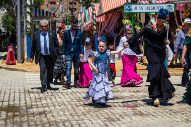 Seville, İspanya - 5 Mayıs 2022 Sevilla 'lılar geleneksel Endülüs tarzında giyinmiş Feria de Seville koridorlarında dolaşıyorlar.