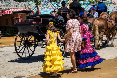 Seville, İspanya - 5 Mayıs 2022 Sevilla 'lılar geleneksel Endülüs tarzında giyinmiş Feria de Seville koridorlarında dolaşıyorlar.