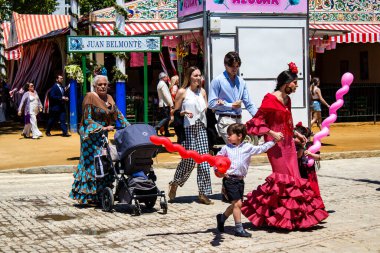 Seville, İspanya - 5 Mayıs 2022 Sevilla 'lılar geleneksel Endülüs tarzında giyinmiş Feria de Seville koridorlarında dolaşıyorlar.