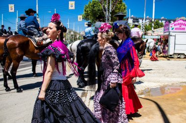 Seville, İspanya - 5 Mayıs 2022 Sevilla 'lılar geleneksel Endülüs tarzında giyinmiş Feria de Seville koridorlarında dolaşıyorlar.