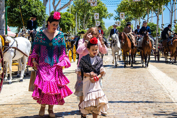 Seville, Spain - May 05, 2022 Sevillians dressed in traditional Andalusian way strolling the aisles of the Feria de Seville, This celebration is back after two years of absence due to covid epidemic