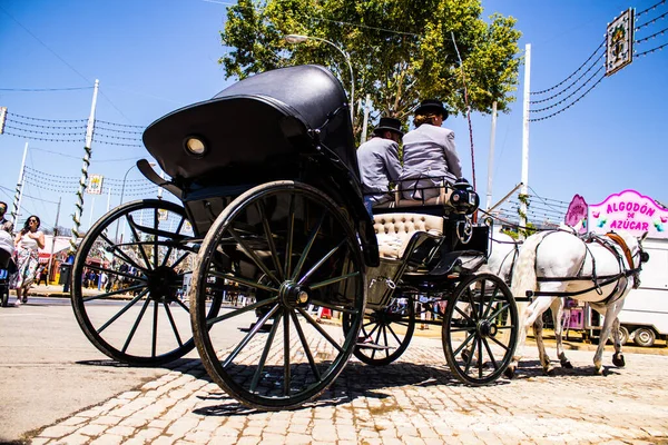 Seville, İspanya - 5 Mayıs 2022 Sevillianlar geleneksel Endülüs tarzında giyinmiş bir şekilde İspanya 'nın en ünlü festivali olan Feria de Sevilla' nın koridorlarında at arabasıyla dolaşıyorlar.