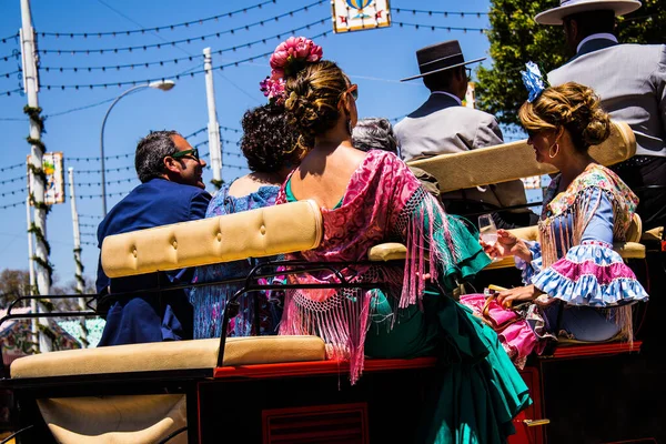 Seville, İspanya - 5 Mayıs 2022 Sevillianlar geleneksel Endülüs tarzında giyinmiş bir şekilde İspanya 'nın en ünlü festivali olan Feria de Sevilla' nın koridorlarında at arabasıyla dolaşıyorlar.