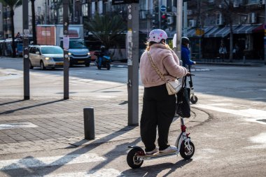 Tel Aviv, İsrail - 07 Mayıs 2022 Tel Aviv sokaklarında elektrikli scooter kullanan insanlar, küçük bir iç yanmalı motorlar ve merkezde bir güverte ile çalışıyorlar.