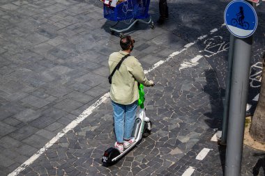 Tel Aviv, Israel - May 07, 2022 People rolling with an electric scooter in the streets of Tel Aviv, operating with a small utility internal combustion engines and a deck in the center