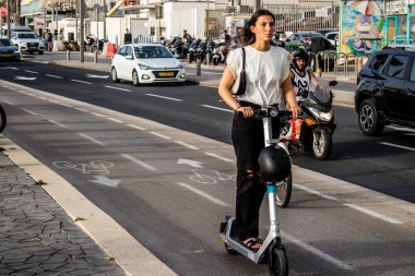 Tel Aviv, Israel - May 07, 2022 People rolling with an electric scooter in the streets of Tel Aviv, operating with a small utility internal combustion engines and a deck in the center