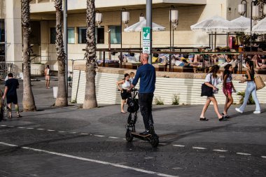 Tel Aviv, Israel - May 07, 2022 People rolling with an electric scooter in the streets of Tel Aviv, operating with a small utility internal combustion engines and a deck in the center