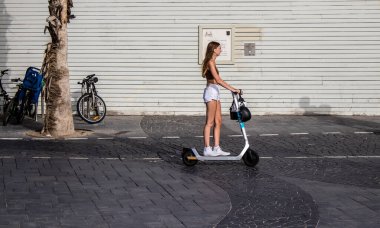Tel Aviv, İsrail - 07 Mayıs 2022 Tel Aviv sokaklarında elektrikli scooter kullanan insanlar, küçük bir iç yanmalı motorlar ve merkezde bir güverte ile çalışıyorlar.