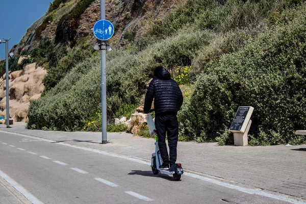 Tel Aviv, İsrail - 07 Mayıs 2022 Tel Aviv sokaklarında elektrikli scooter kullanan insanlar, küçük bir iç yanmalı motorlar ve merkezde bir güverte ile çalışıyorlar.