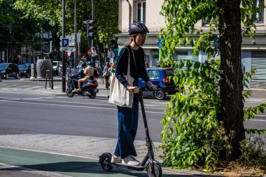 Paris, Fransa - 21 Mayıs 2022 Paris sokaklarında elektrikli scooterla dolaşan insanlar, küçük bir iç yanmalı motorlar ve merkezde bir güverte ile çalışıyorlar.
