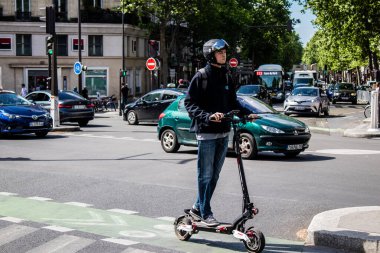 Paris, Fransa - 21 Mayıs 2022 Paris sokaklarında elektrikli scooterla dolaşan insanlar, küçük bir iç yanmalı motorlar ve merkezde bir güverte ile çalışıyorlar.