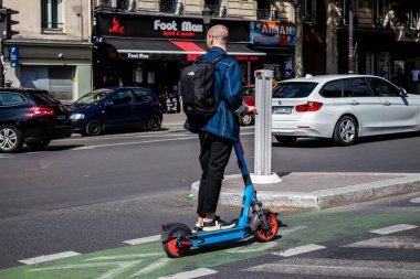 Paris, Fransa - 21 Mayıs 2022 Paris sokaklarında elektrikli scooterla dolaşan insanlar, küçük bir iç yanmalı motorlar ve merkezde bir güverte ile çalışıyorlar.