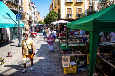 Seville, İspanya - 14 Temmuz 2022 Mercadillo Historico Del Jueves olarak da bilinen bit pazarında satılan çeşitli eşyalar, yerel halk dar Calle Feria 'da pazarlık aramakla meşgul.