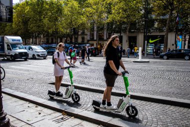 Paris, France - September 05, 2022 People rolling with an electric scooter in the streets of Paris, operating with a small utility internal combustion engines and a deck in the center