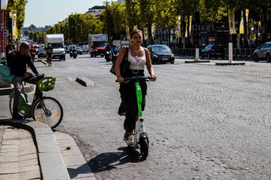 Paris, France - September 05, 2022 People rolling with an electric scooter in the streets of Paris, operating with a small utility internal combustion engines and a deck in the center