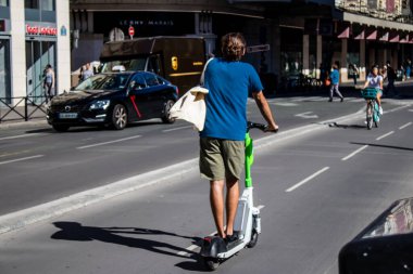 Paris, Fransa - 14 Eylül 2022 Paris sokaklarında elektrikli scooterla dolaşan insanlar, küçük bir iç yanmalı motorlar ve merkezde bir güverte ile çalışıyorlar.