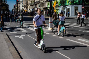 Paris, Fransa - 14 Eylül 2022 Paris sokaklarında elektrikli scooterla dolaşan insanlar, küçük bir iç yanmalı motorlar ve merkezde bir güverte ile çalışıyorlar.