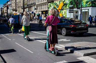 Paris, Fransa - 14 Eylül 2022 Paris sokaklarında elektrikli scooterla dolaşan insanlar, küçük bir iç yanmalı motorlar ve merkezde bir güverte ile çalışıyorlar.