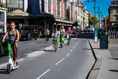 Paris, Fransa - 14 Eylül 2022 Paris sokaklarında elektrikli scooterla dolaşan insanlar, küçük bir iç yanmalı motorlar ve merkezde bir güverte ile çalışıyorlar.