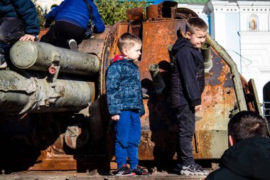 Ukrayna, Kyiv 'deki Mykhailivska Meydanı' ndaki imha edilmiş Rus askeri teçhizatı sergisinde, 16 Ekim 2022 Ukraynalı çocuklar imha edilmiş Rus askeri teçhizatıyla eğleniyorlar, bunu bir oyun grubu olarak kullanıyorlar.