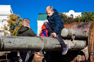 Ukrayna, Kyiv 'deki Mykhailivska Meydanı' ndaki imha edilmiş Rus askeri teçhizatı sergisinde, 16 Ekim 2022 Ukraynalı çocuklar imha edilmiş Rus askeri teçhizatıyla eğleniyorlar, bunu bir oyun grubu olarak kullanıyorlar.