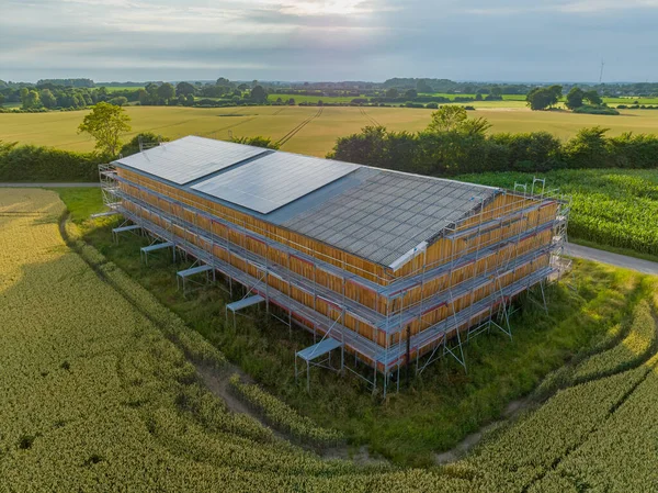 Solar panels on farm barn. Agriculture barn under renovation works with construction scaffolding frame. Currently renovated barn with photovoltaic module on the rooftop. Solar panel, photovoltaic.