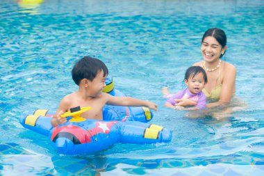 Yüzme havuzunda dinlenen şişme yüzüklü mutlu bir aile, Asyalı insanlar.