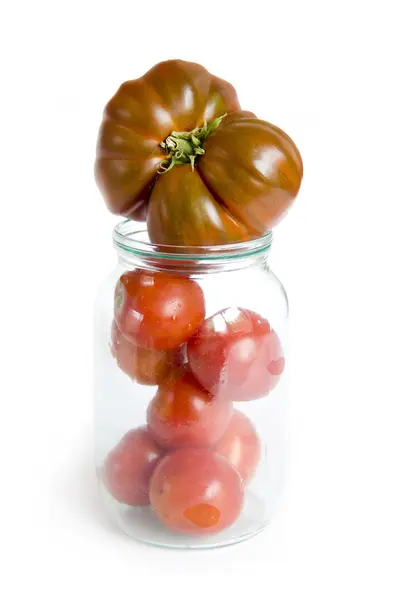 Large and small tomatoes in glass jar — Stock Photo, Image