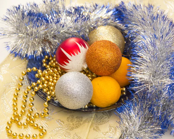 Tangerines and Christmas tree ornaments on a blue plate — Stock Photo, Image