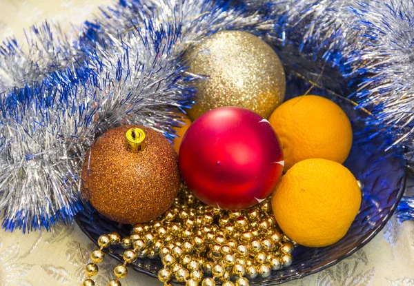 Tangerines and Christmas tree ornaments on a blue plate — Stock Photo, Image