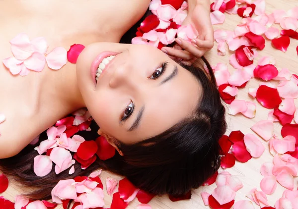 Meisje glimlachend gezicht met rose achtergrond — Stockfoto