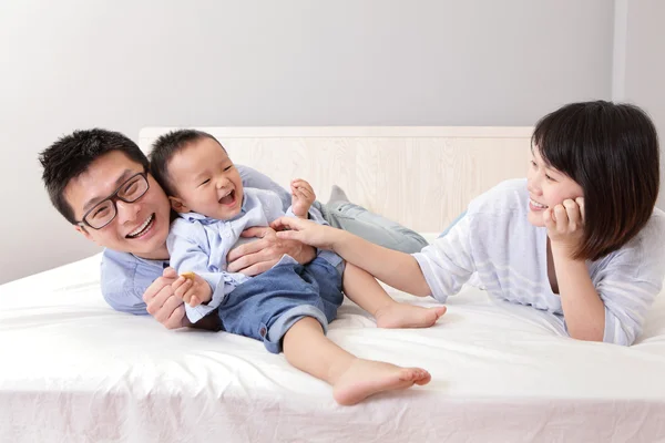 Šťastná rodina hraje na bílé posteli — Stock fotografie