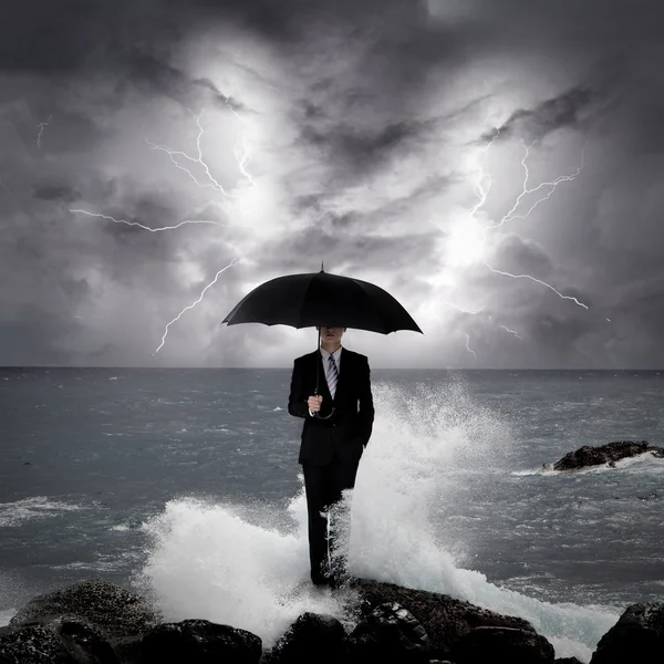 Uomo d'affari sotto un ombrello nel mare Foto Stock