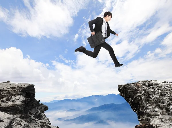 Businessman jumping over danger precipice — Stock Photo, Image