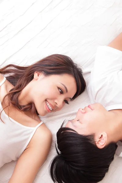 ベッドの中でお互いに見ているカップル幸せな笑顔 — ストック写真