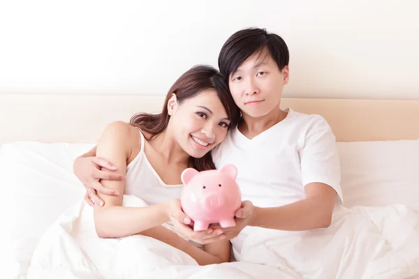 Casal feliz com o banco piggy rosa — Fotografia de Stock