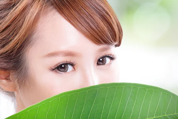 Vacker kvinna ansikte stående med grönt blad — Stockfoto
