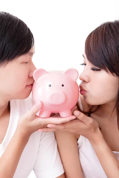 Young happy couple kiss pink piggy bank — Stock Photo, Image