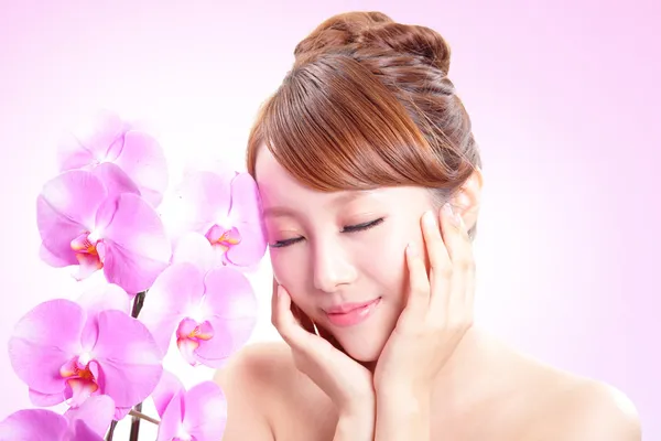 Женщина улыбается лицо с орхидеей цветы — стоковое фото