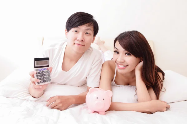 Happy couple with pink piggy bank and calculator — Stock Photo, Image