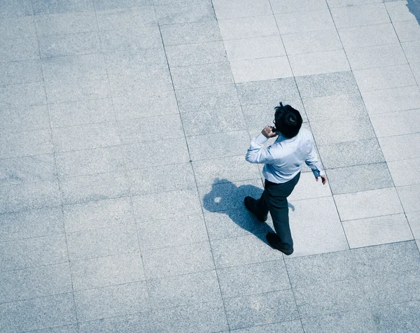 Uomo d'affari a piedi e utilizzando smart phone — Foto Stock