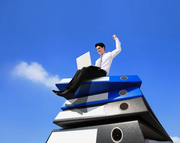 Business man using notebook computer and sitting on lots piles of document folders — Stock Photo, Image