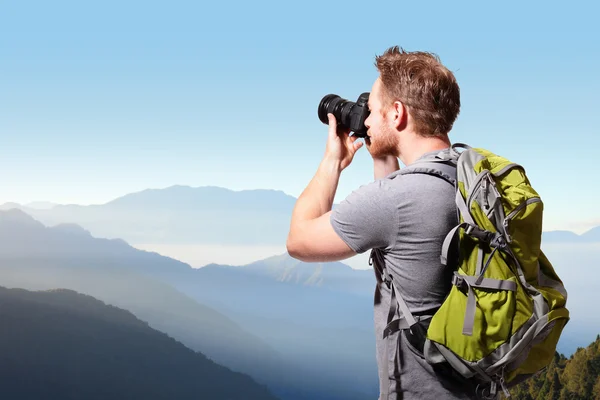 Ung man tar foto på toppen av berget — Stockfoto
