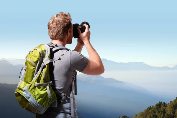 Joven tomando fotos en la cima de la montaña — Foto de Stock