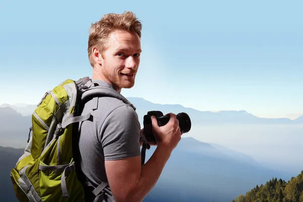 Молодой человек фотографирует на вершине горы — стоковое фото