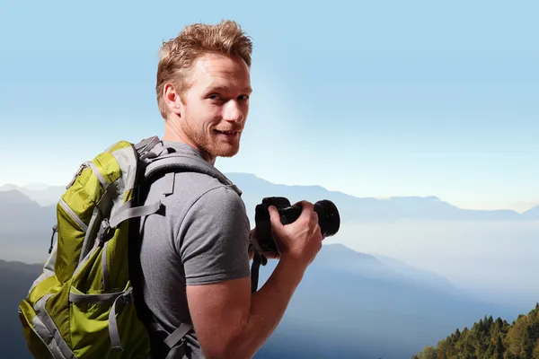 Young man taking photo on top of mountain — Stock Photo, Image