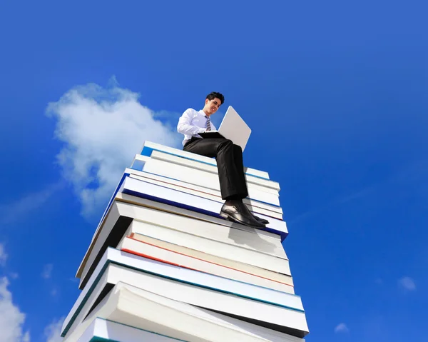 Hombre de negocios feliz usando ordenador PC y sentado en una pila de libros — Foto de Stock