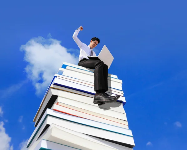 Hombre de negocios feliz usando ordenador PC y sentado en una pila de libros —  Fotos de Stock