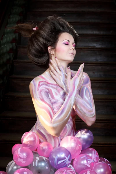 Indoor shoot with young caucasian woman posing in fantasy style dressed to pink body art and air balloon skirt — Stock Photo, Image